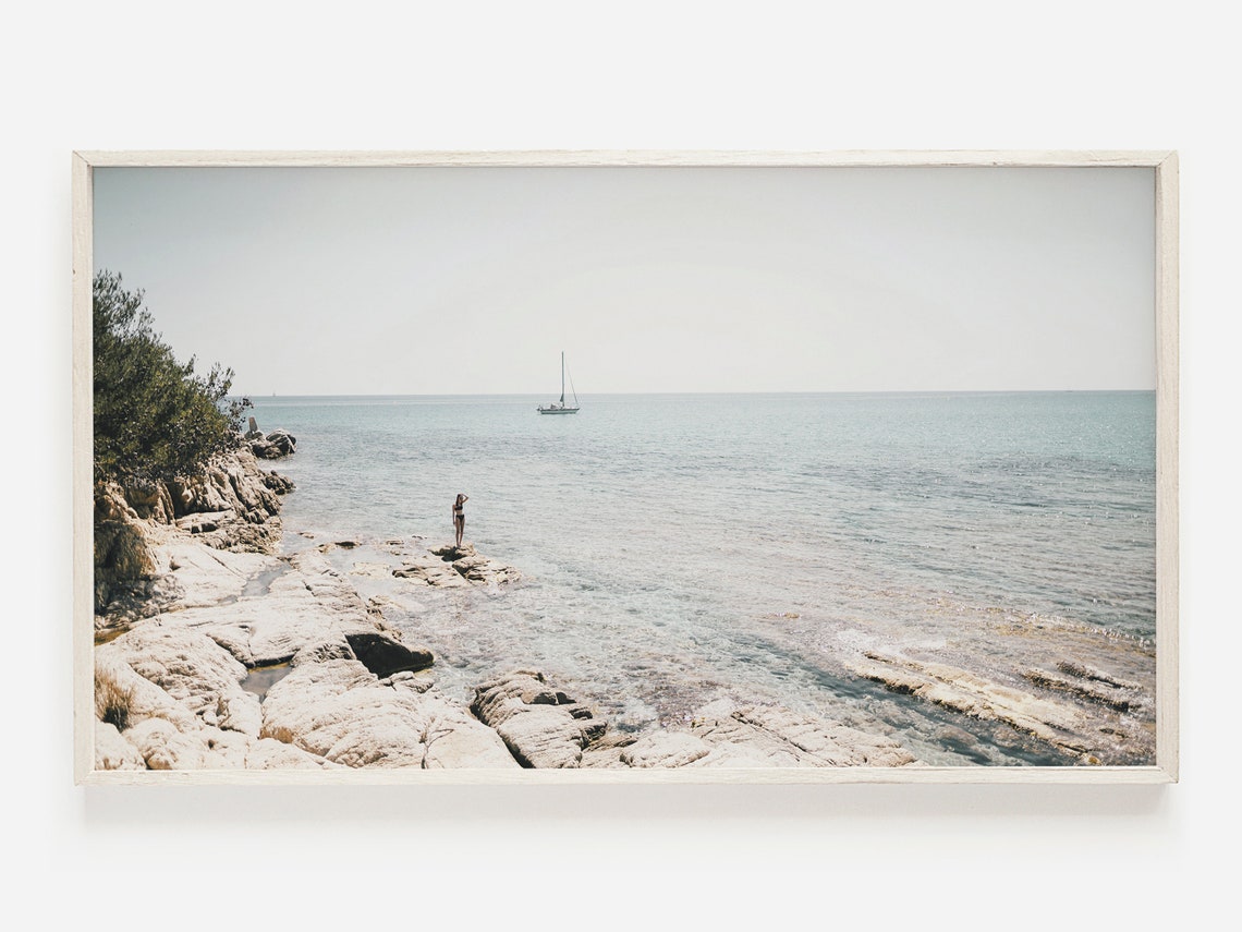 Rocky Coastline With Distant Sailboat In Calm Turquoise Sea Poster