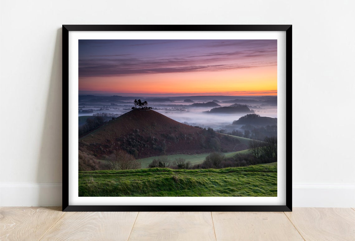 Sunrise Over a Misty Valley With Lone Trees on a Green Hilltop Poster