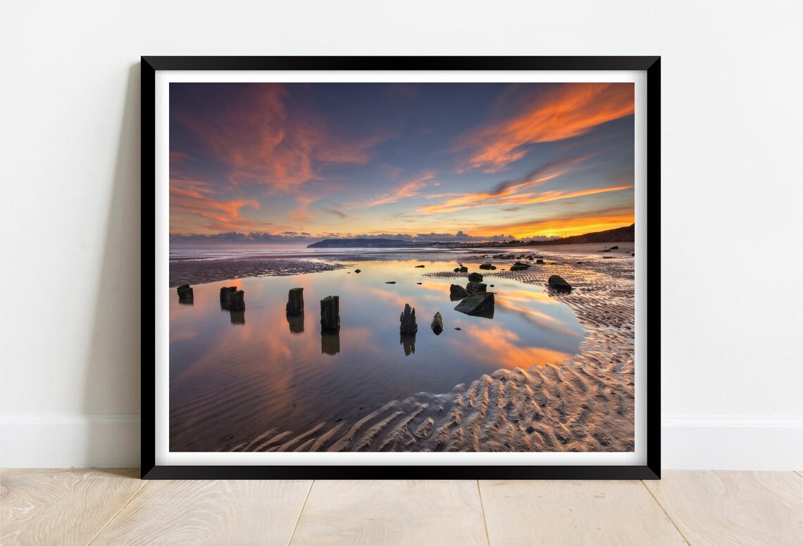 Old Wooden Groynes on Wet Sand at Sunset with Reflections Poster