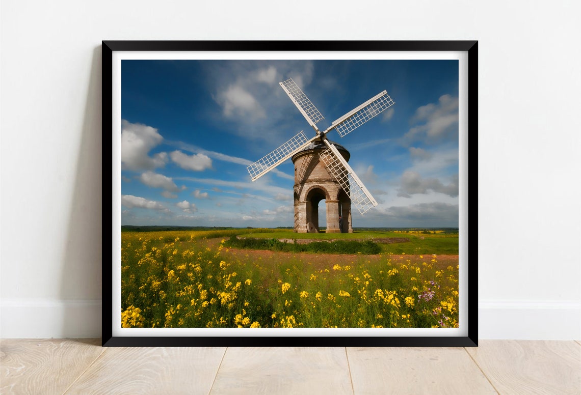 Historic Stone Windmill in a Wildflower Meadow Under Blue Sky Poster