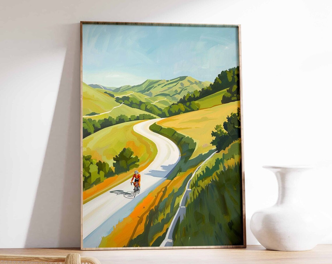 Solo Cyclist Riding Winding Road Through Golden Rolling Hills Poster