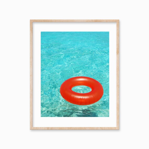 Bright Orange Pool Float Ring Floating in Turquoise Water Poster