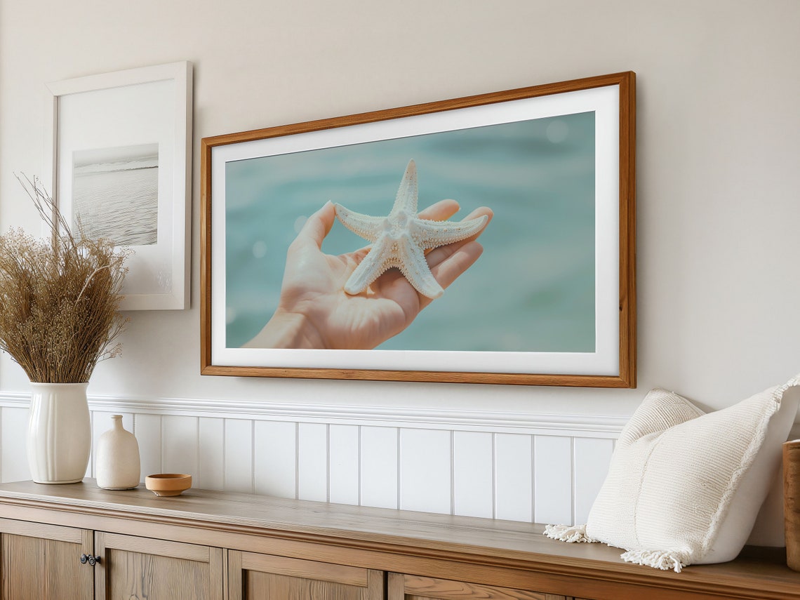 Hand Gently Holding a White Starfish Over the Turquoise Sea Poster - Image 3
