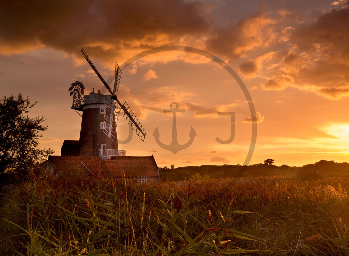 Historic Windmill Silhouetted Against a Fiery Orange Sunset Sky Poster - Image 3