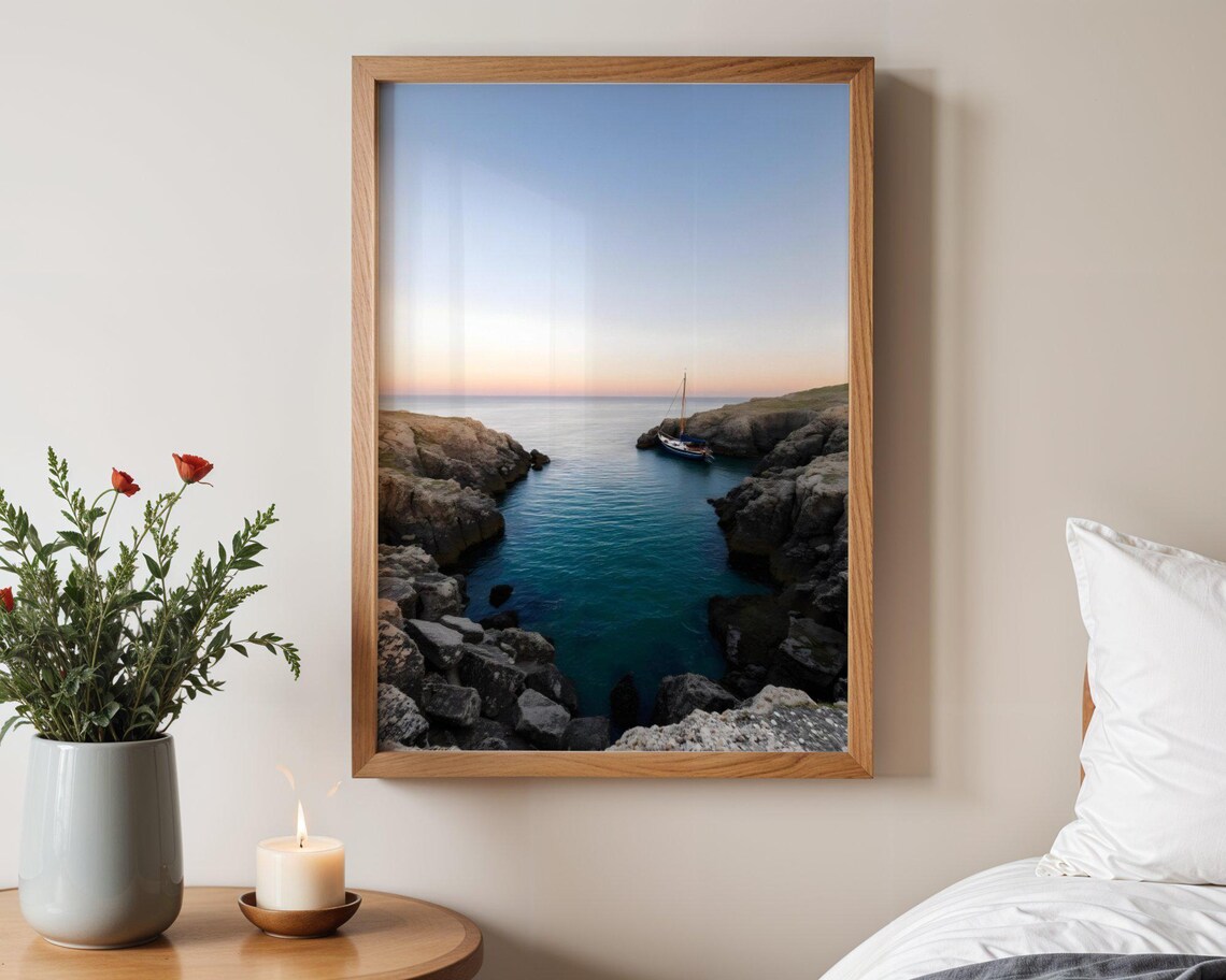 Lone Sailboat Anchored in a Rocky Coastal Cove at Dusk Poster