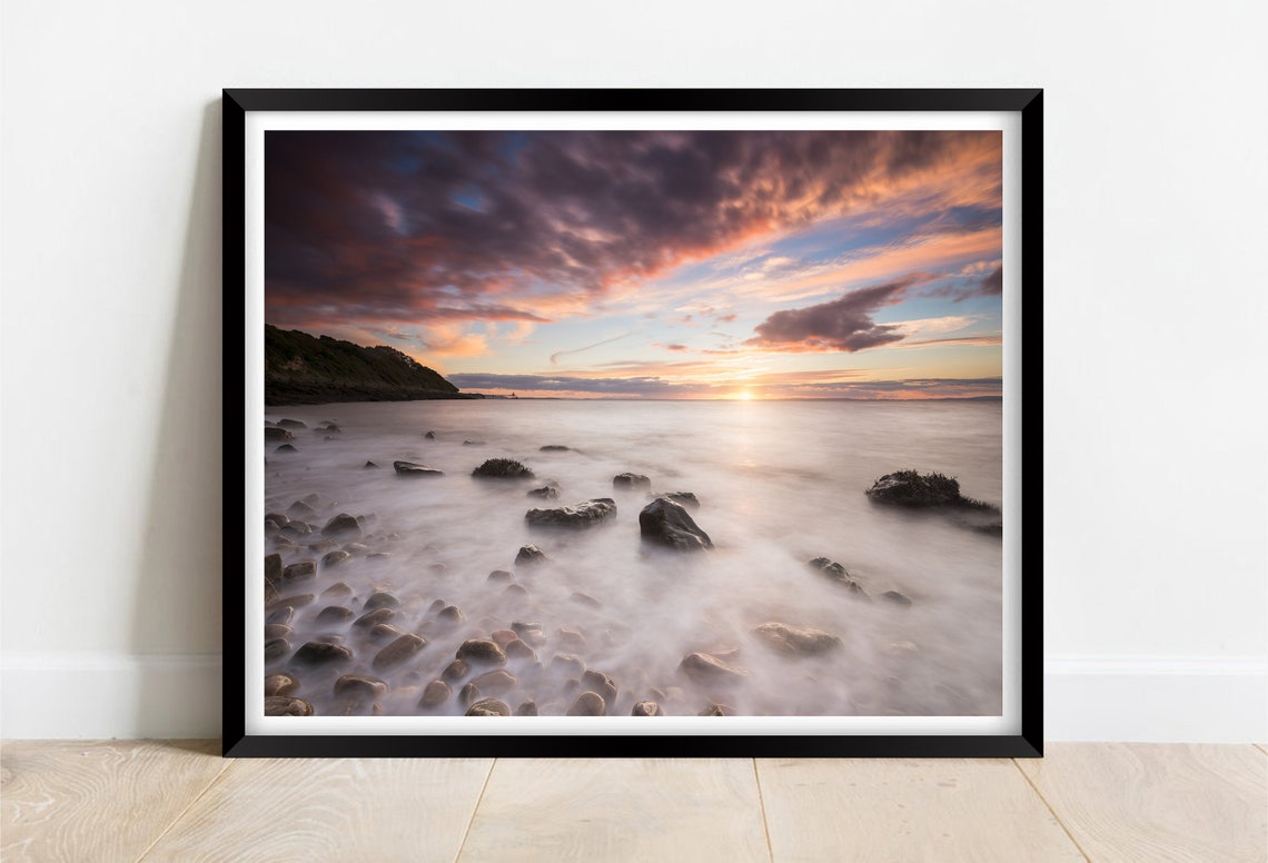 Dramatic Sunset Over Rocky Shoreline with Long Exposure Poster