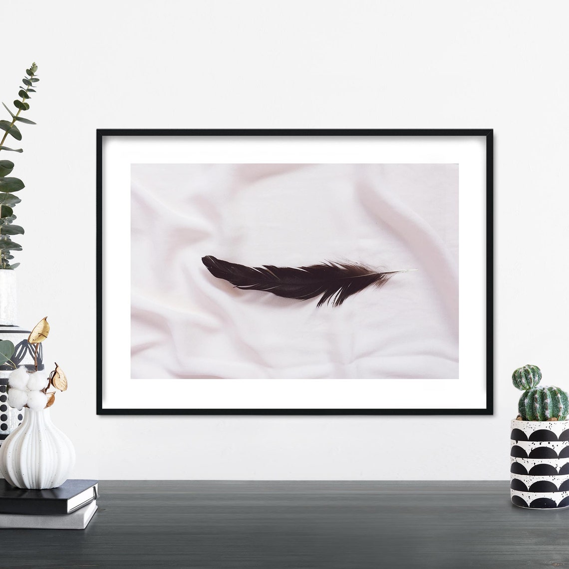 Single Dark Feather Resting on Soft White Fabric Minimalist Print