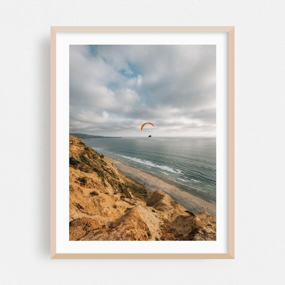 Orange Paraglider over San Diego Ocean Poster from Rocky Cliffs