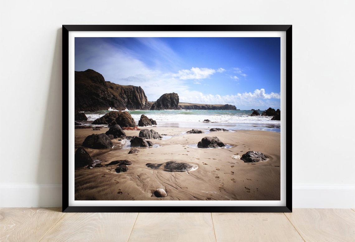 Rocky Beach Cove with a Towering Sea Stack Under a Blue Sky Poster