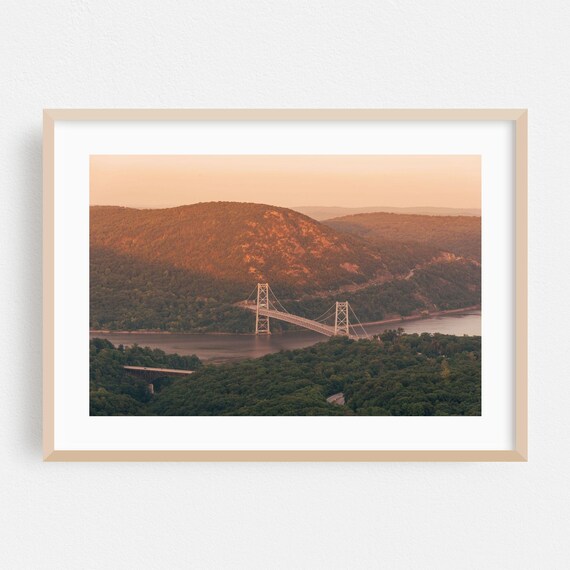 Suspension Bridge Spanning A Wide River Canyon At Sunset Poster