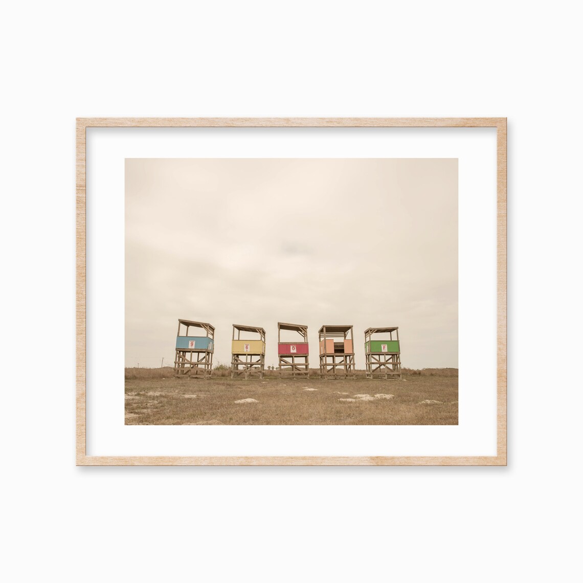 Row of Colorful Lifeguard Towers on a Beach Under Grey Sky Poster