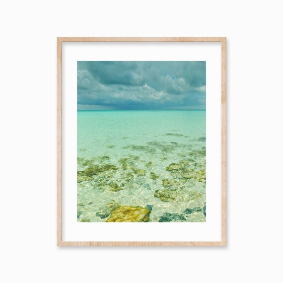 Crystal Clear Shallow Sea with Rocks Under Storm Clouds Poster