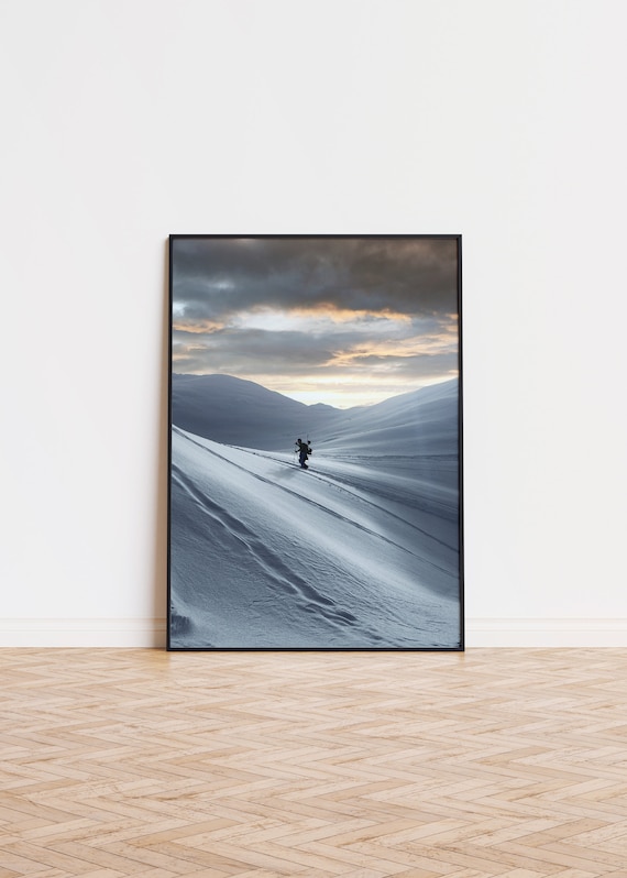 Solo Hiker Climbing Snowy Mountain Slope at Golden Sunset Poster