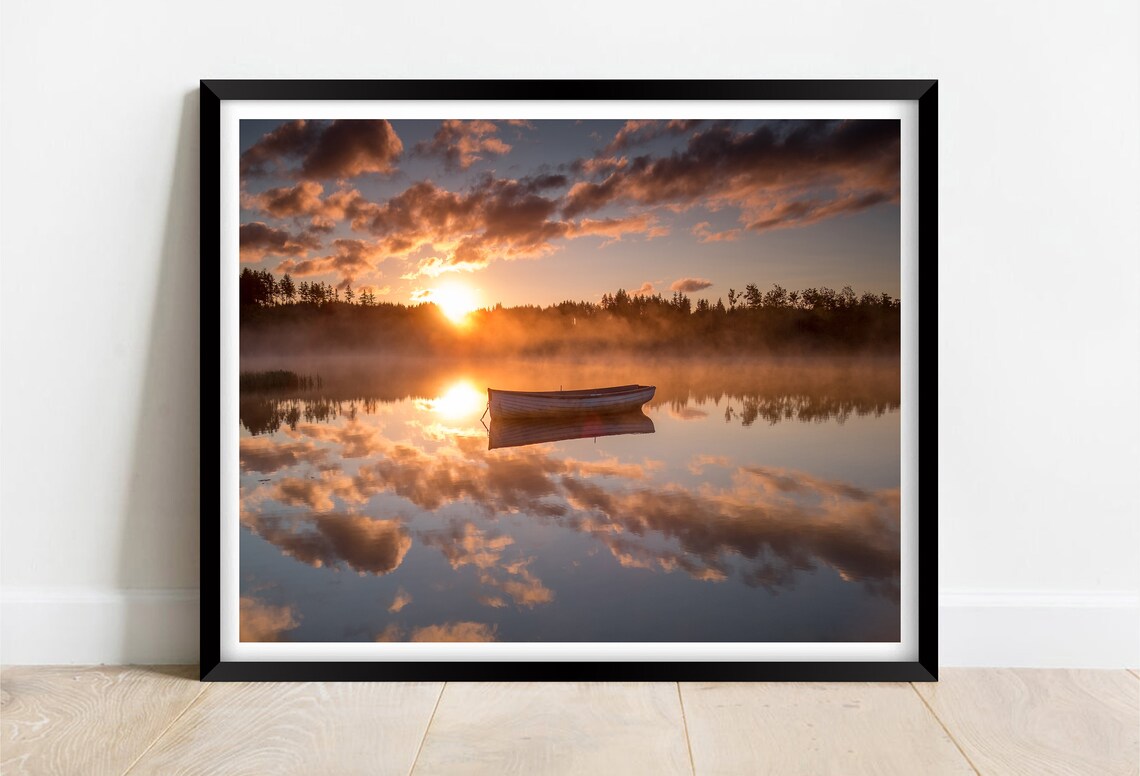 Lone Wooden Rowboat on a Misty Lake at Golden Sunrise Poster