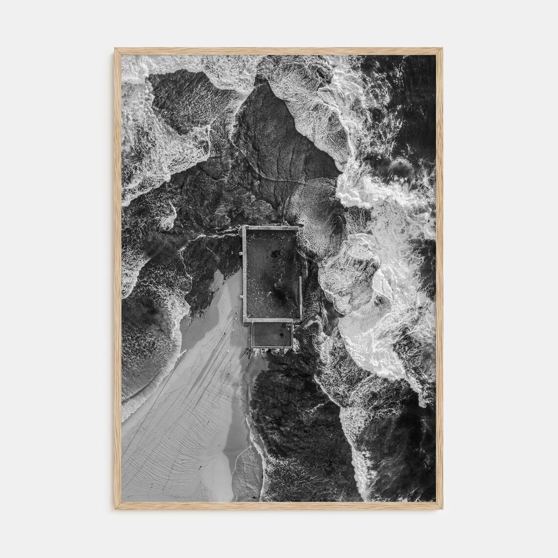 Black and White Aerial View of Waves Crashing on Rocky Shore Poster