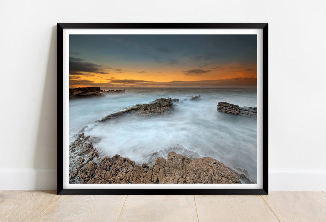 Long Exposure Waves Washing Over a Rocky Shore at Sunset Poster