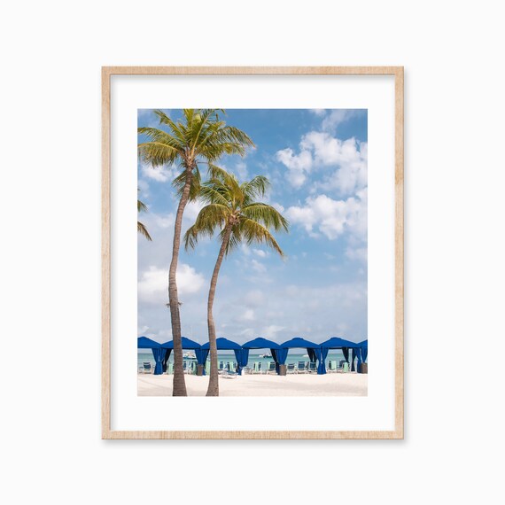 Leaning Palm Trees and Blue Beach Cabanas by the Ocean Poster