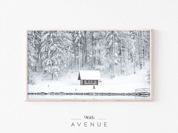 Wooden Cabin on Frozen Lake Surrounded by Snowy Trees Poster