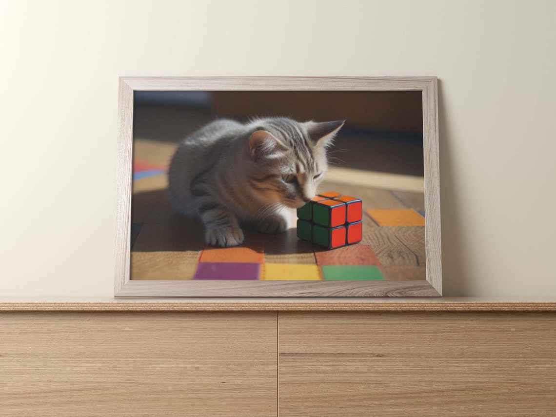 Gray Tabby Kitten Resting Beside A Small Red Rubiks Cube Poster - Image 2